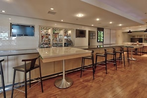 A bar area with a long counter, multiple stools, and a television mounted on the wall. - Holiday Inn Roswell by IHG (Roswell)