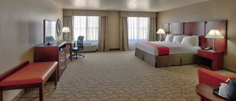 A hotel room with a bed, desk, chair, and a television.