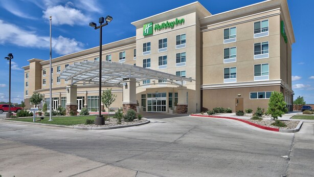 A Holiday Inn hotel with a covered entrance, multiple floors, and a clear blue sky.