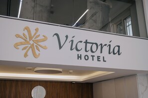 Une enseigne pour l’hôtel Victoria, avec un logo stylisé et le nom écrit dans une police de caractères moderne.