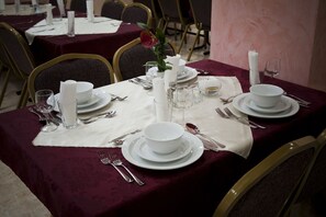 Une table à manger dressée avec de l’assiette, des bols et des couverts blancs, ainsi qu’un vase rempli de fleurs et des bougies.
