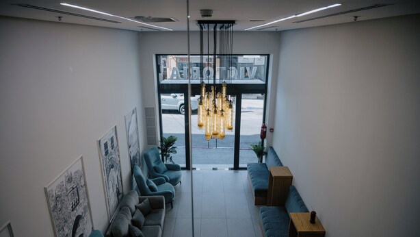 Een moderne lobby met een zithoek, een groot raam met uitzicht op de straat en een unieke hanglamp.