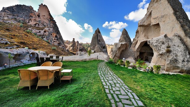 A garden with a paved pathway, outdoor furniture, and rock formations.