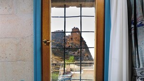 A door with a view of a rocky landscape through a grid pattern.