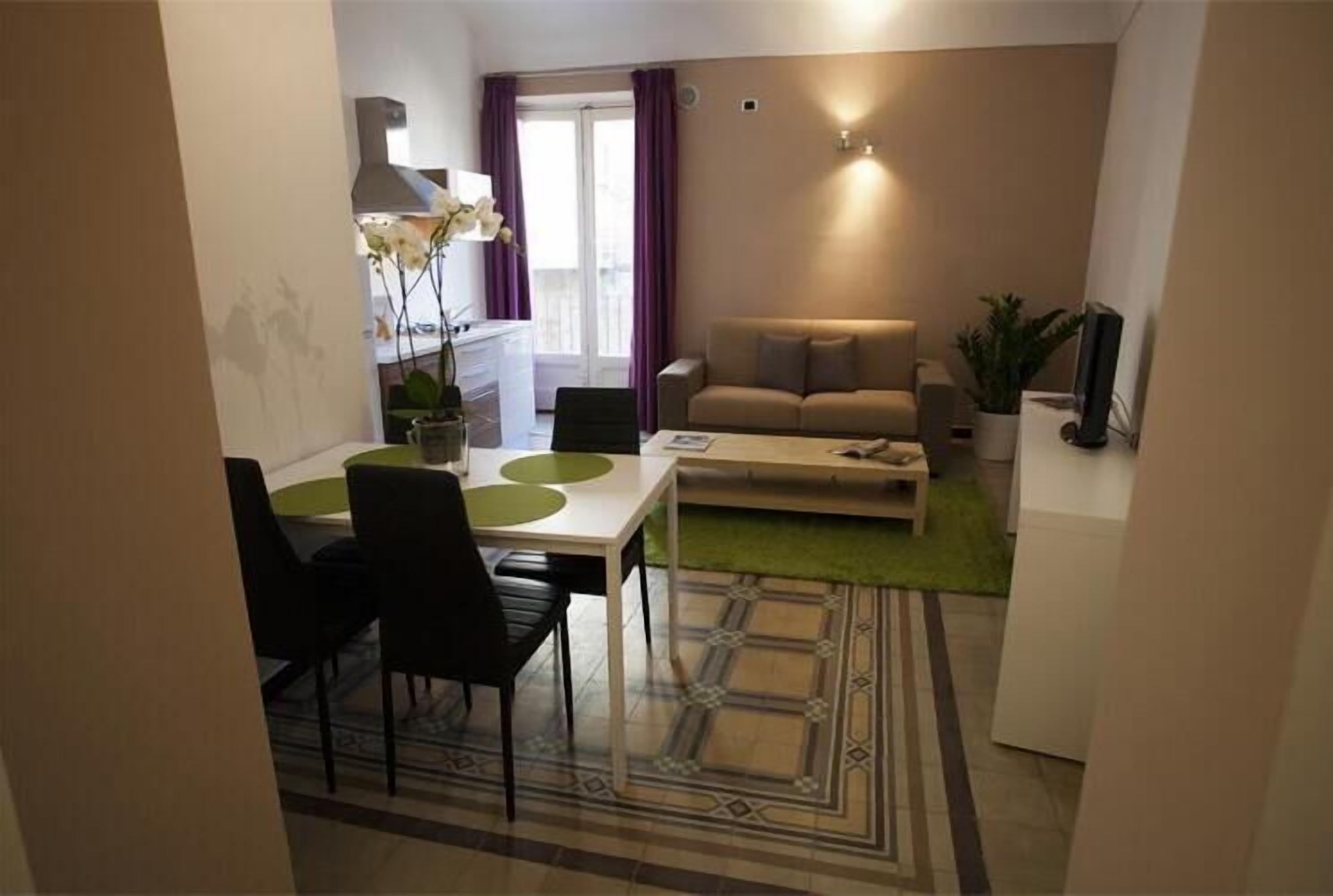 En moderne stue med sofa, sofabord og spiseområde med stole og bord.