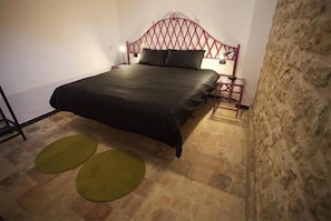 Une chambre à coucher avec un lit, une table de chevet, une lampe et deux tapis verts.