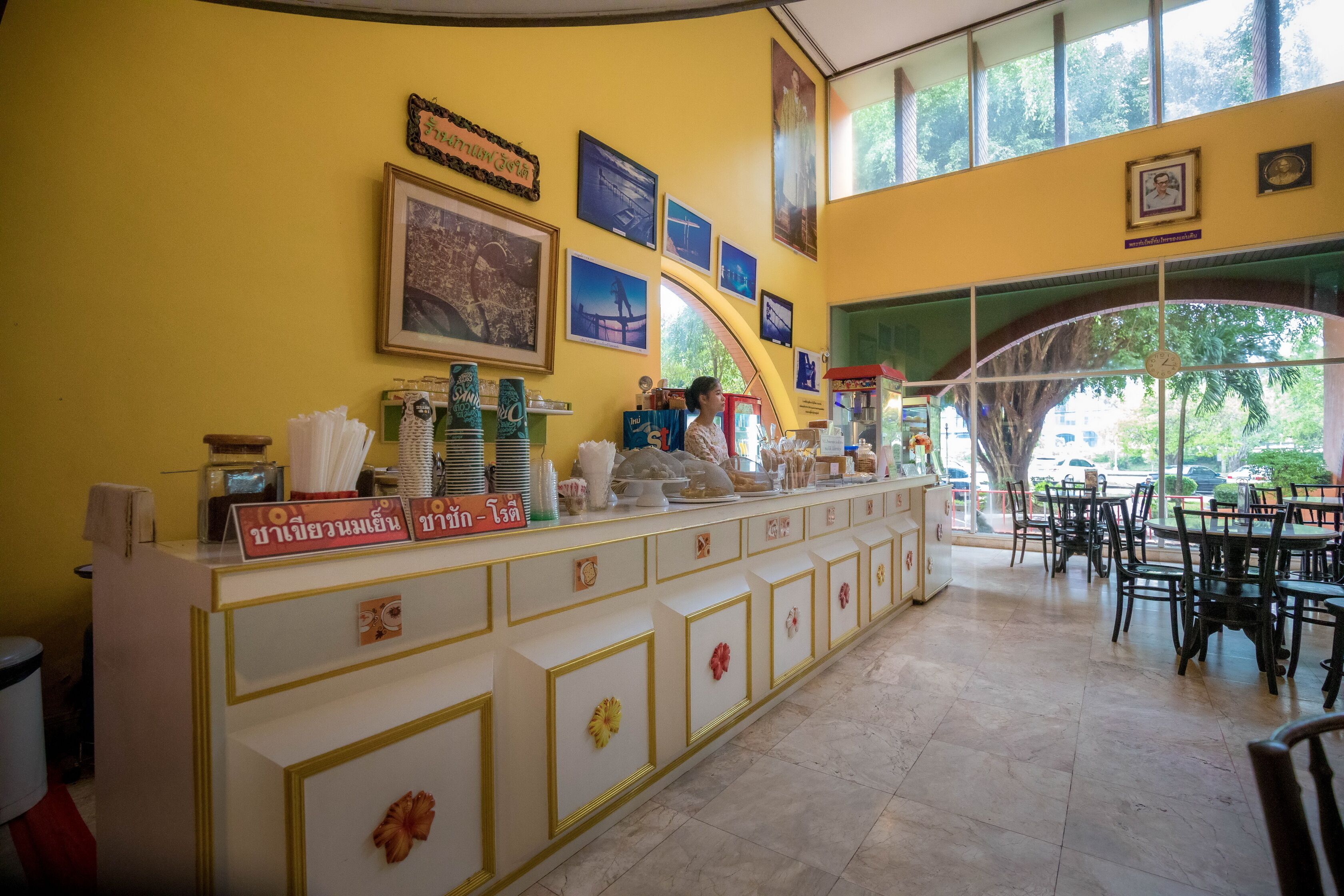 Un restaurante con pared amarilla, cuadros enmarcados y una barra con diversos artículos.