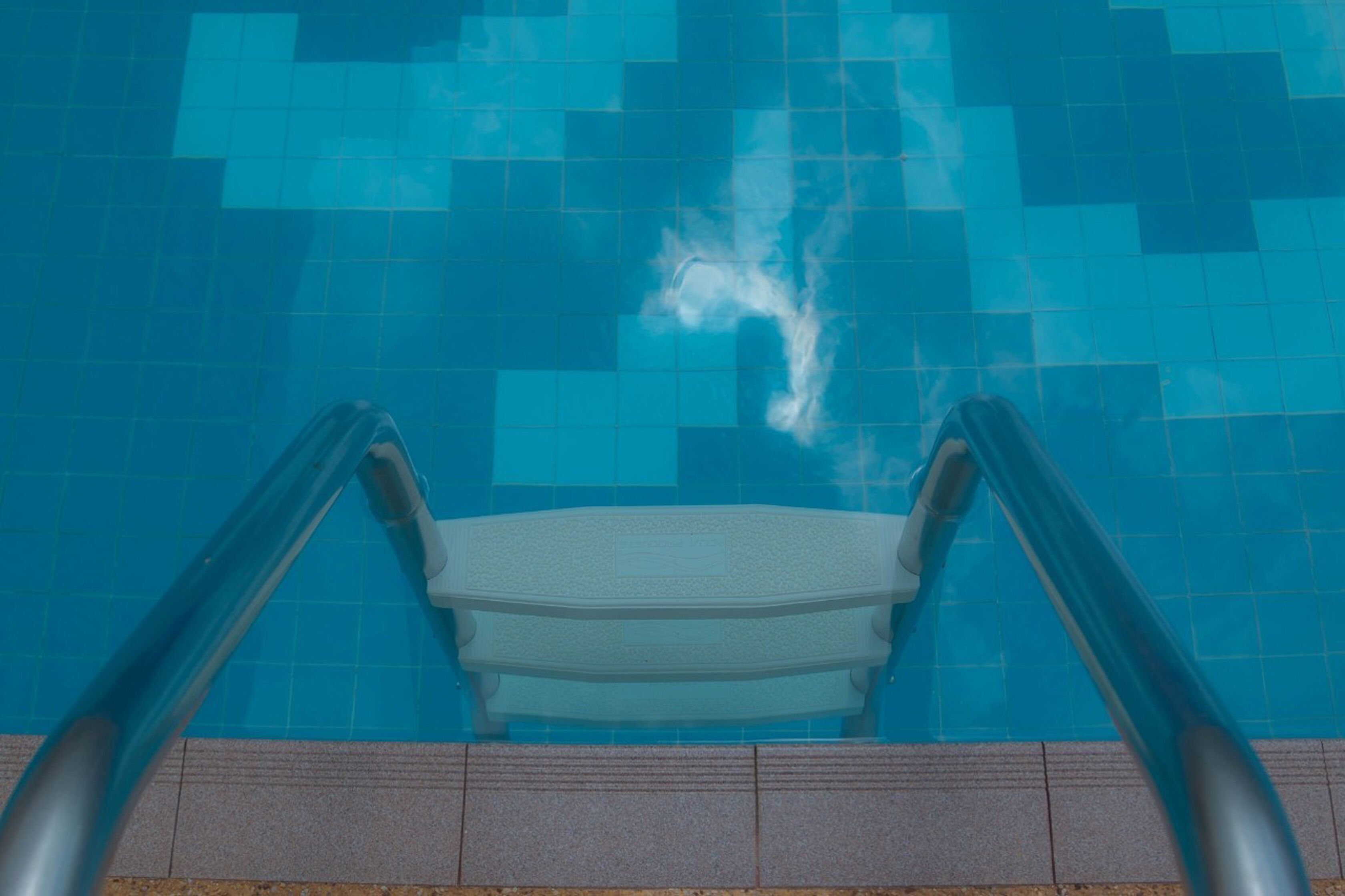 Ein Pool mit blauen Fliesen und einer weißen Sitzbank.