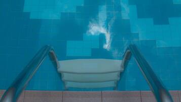 Ein Pool mit blauen Fliesen und einer weißen Sitzbank.
