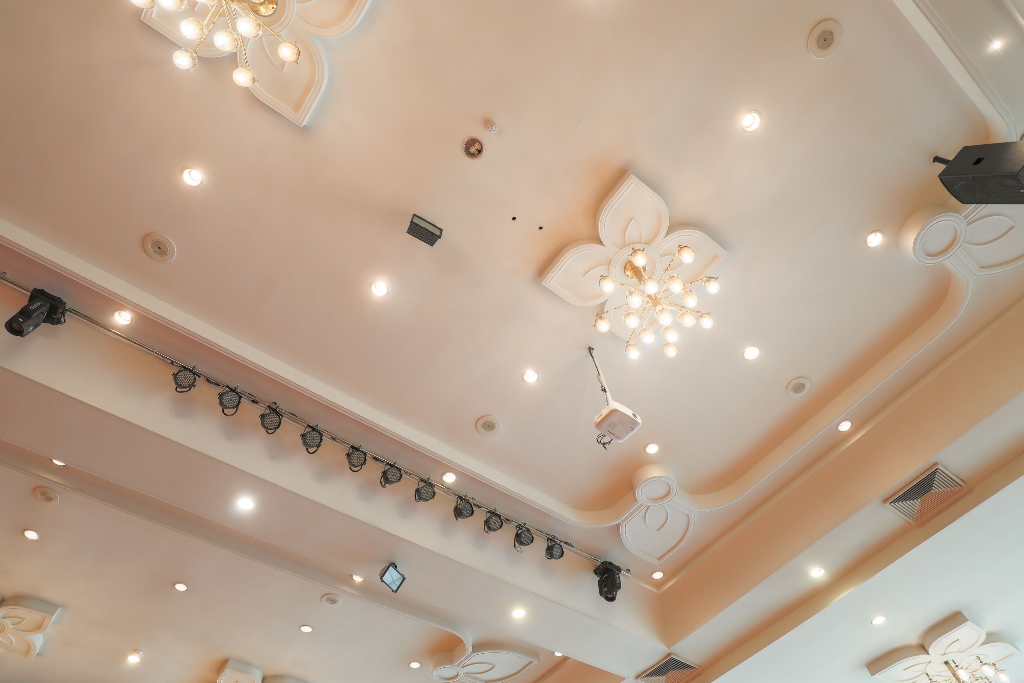 A ceiling with recessed lighting, decorative chandeliers, and a track lighting system.
