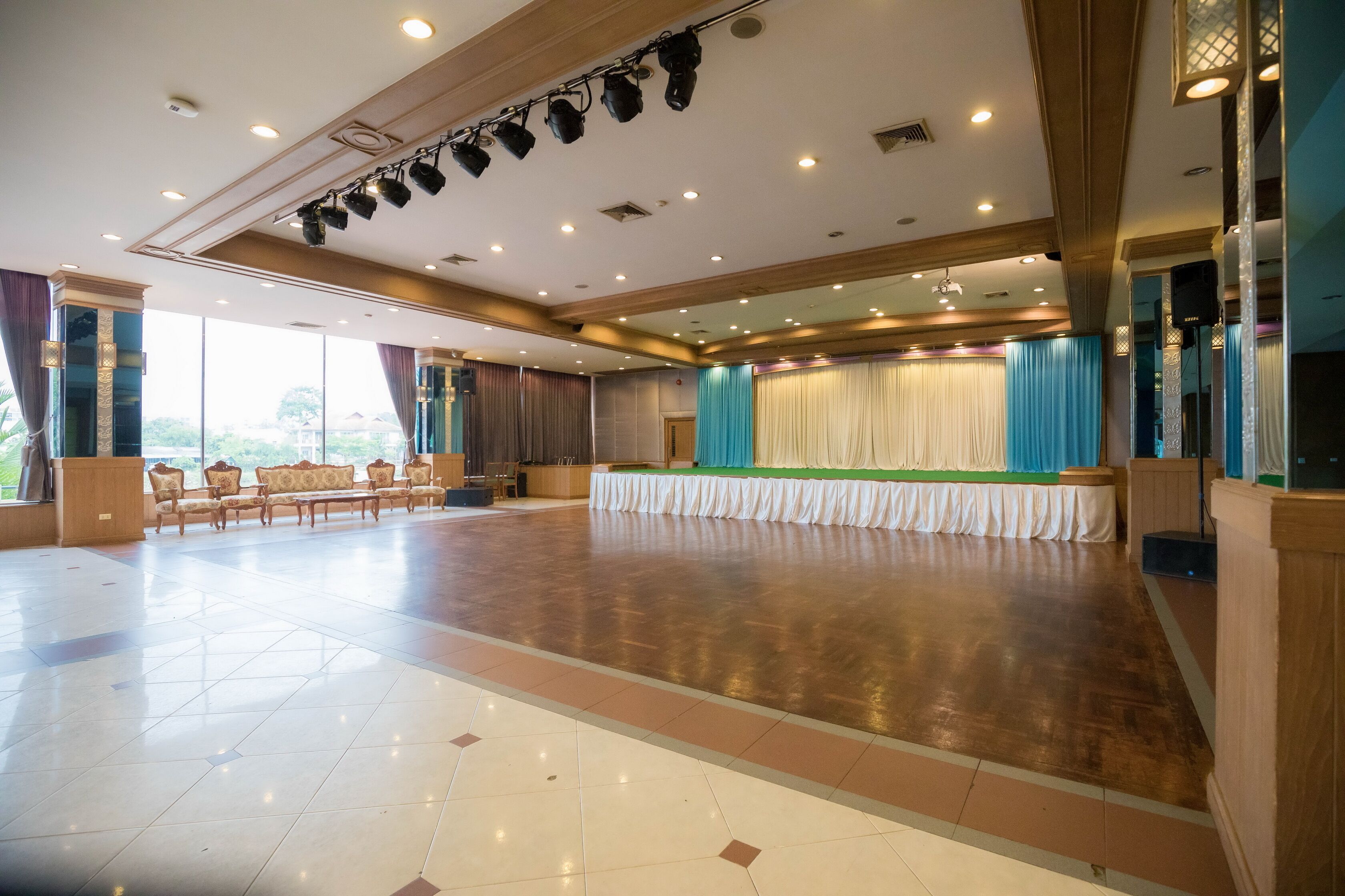 Un salón amplio con un escenario, filas de sillas y suelo de madera.