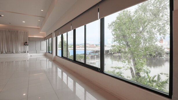 A spacious, modern hotel room with large windows offering a view of a body of water and greenery. - Wangtai Hotel (Surat Thani)
