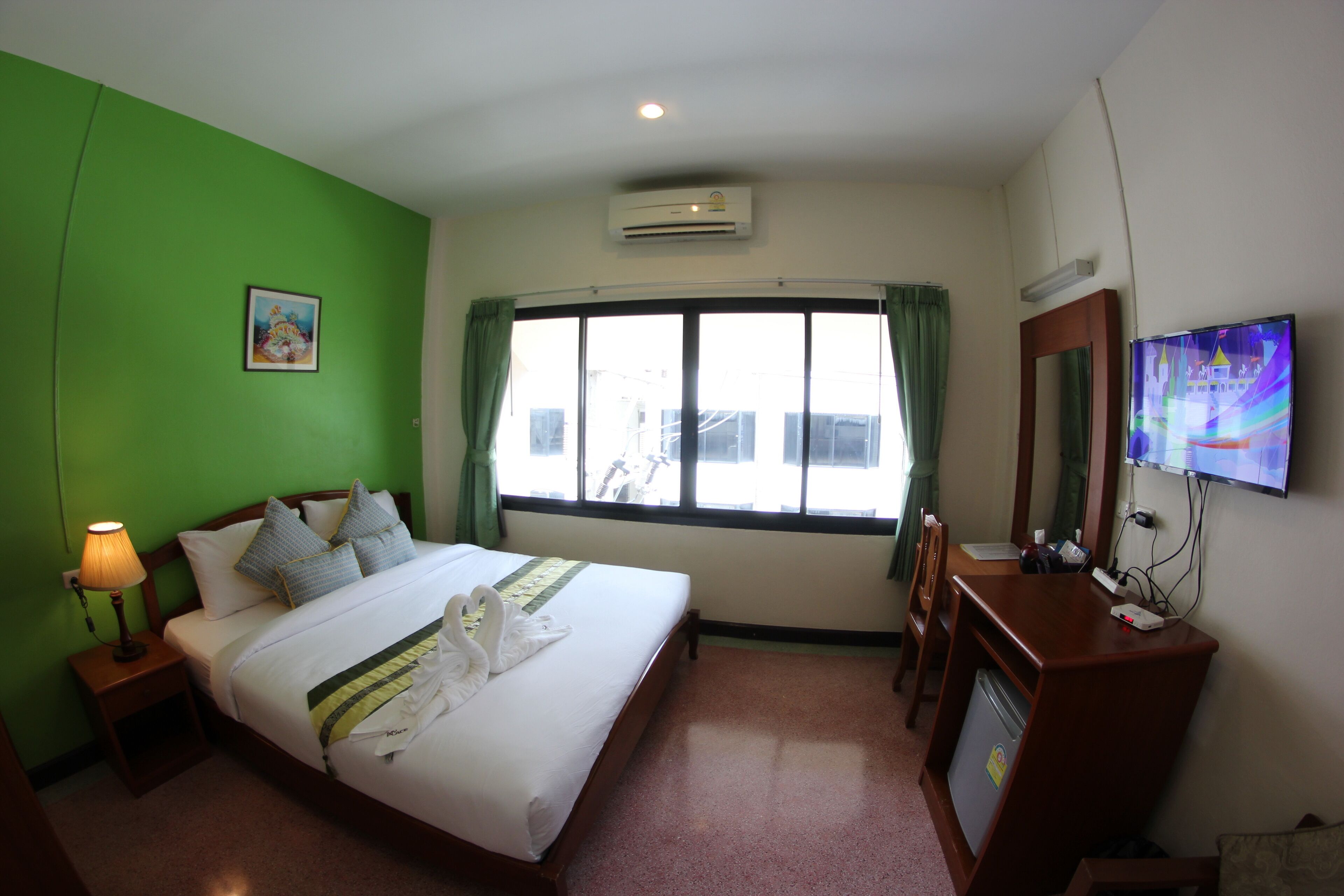 A hotel room with a bed, a desk, a television, and a window with curtains.