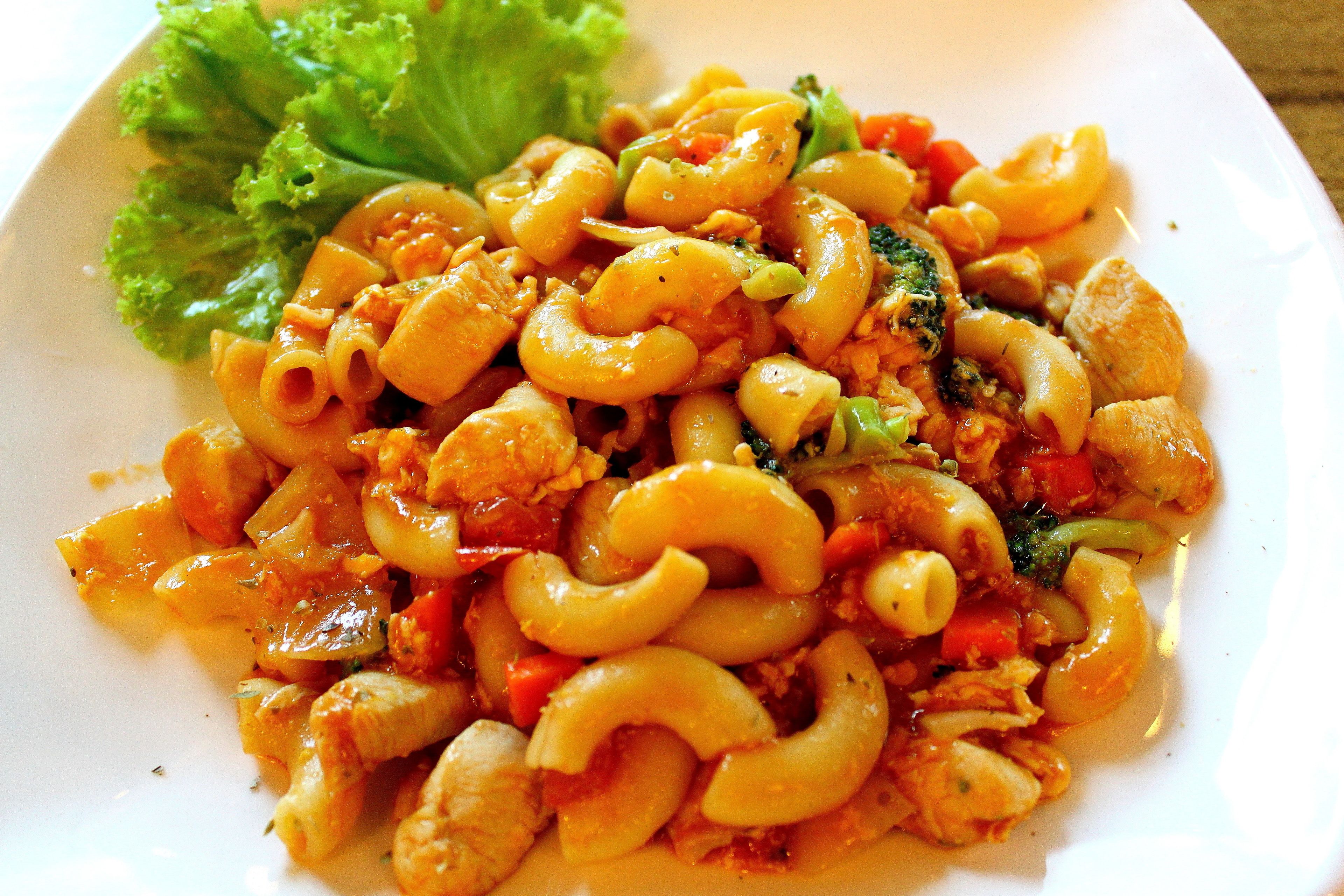 A plate of pasta with vegetables and a side of lettuce.