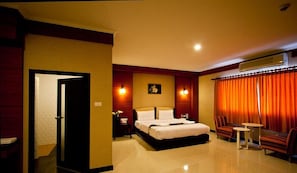 Une chambre d’hôtel comprenant un lit, une table de chevet, une chaise, une petite table et un appareil de climatisation.