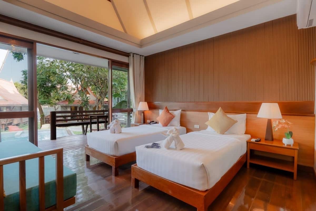 A hotel room with two beds, wooden headboards, and a large window offering a view of the outdoors.