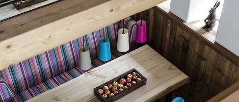 A wooden dining table with a fruit tray, a striped sofa, and a small rabbit figurine.