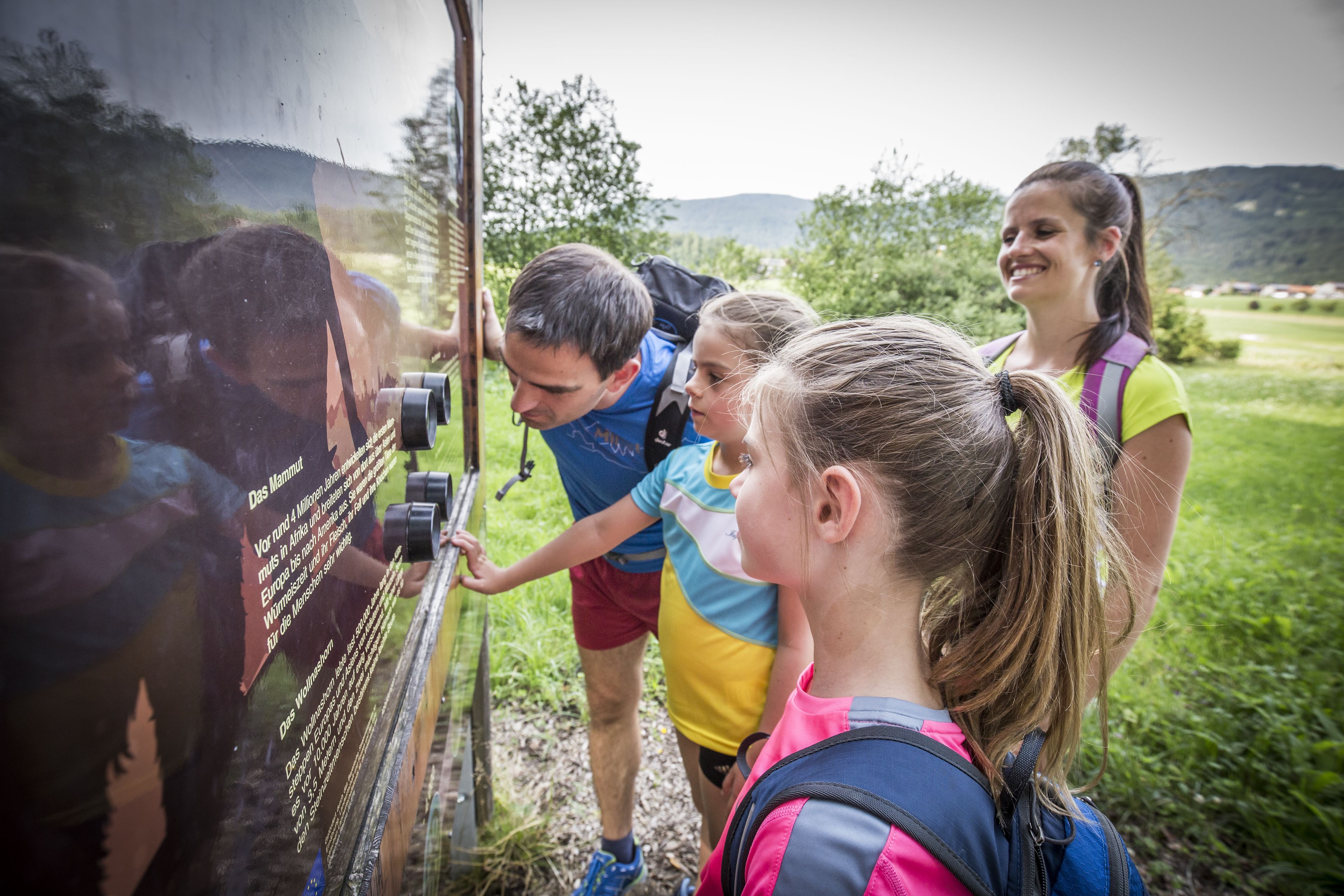 Un groupe de personnes monte dans un autobus, avec en arrière-plan un paysage verdoyant et des collines.