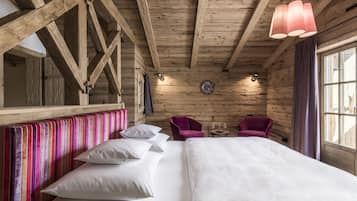 A wooden cabin-style room with a bed, two chairs, and a small table.