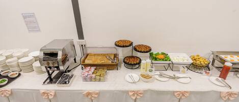 A buffet table with various food items, plates, and utensils.