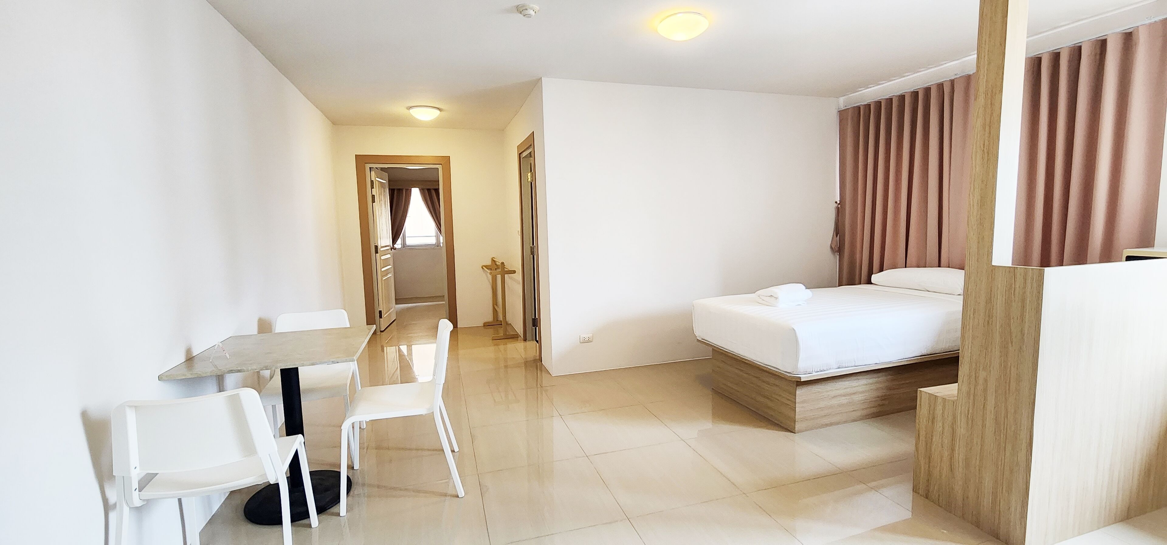 A modern hotel room with a bed, a small table, and two chairs.