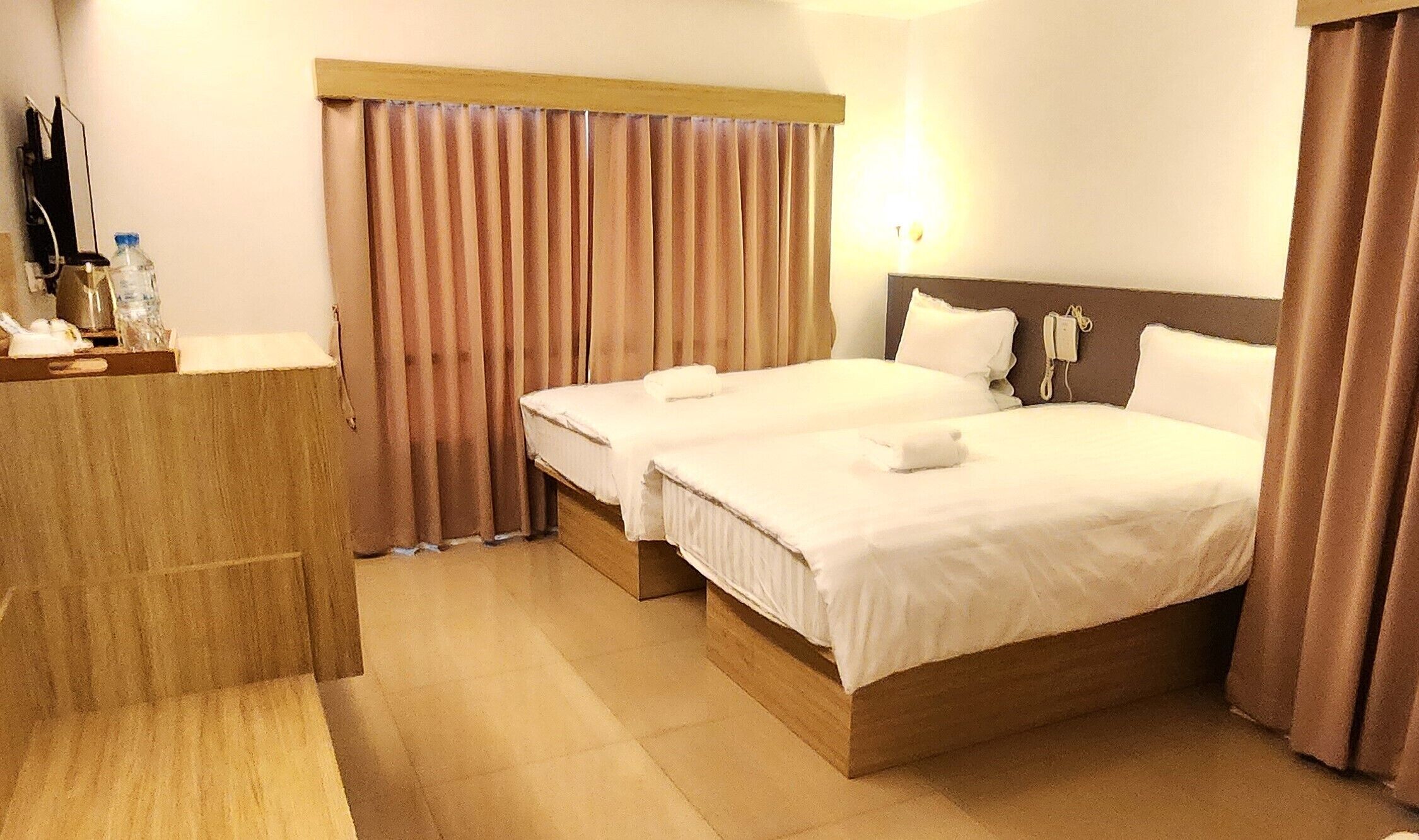 Quarto de hotel com duas camas, uma escrivaninha e um telefone.