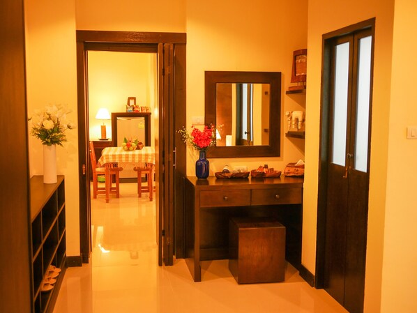 A hallway with a dining area, a mirror, and a small cabinet.