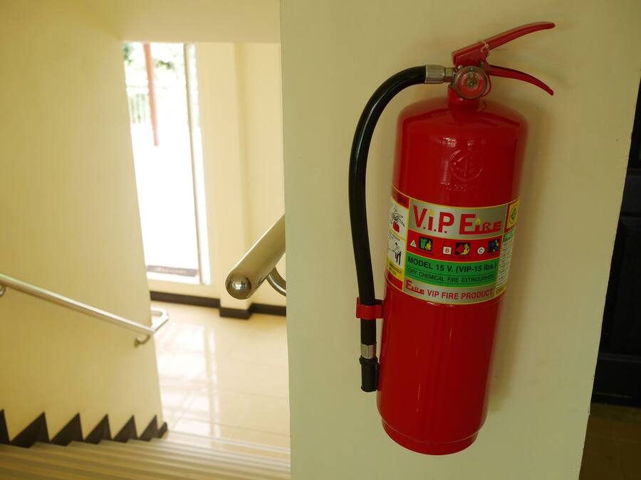 A red fire extinguisher mounted on a wall in a hallway.