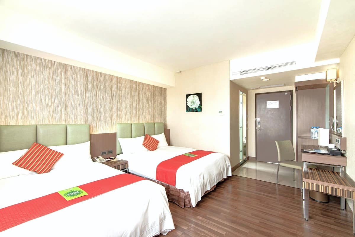 Une chambre d’hôtel avec deux lits, un bureau, une chaise et une porte.