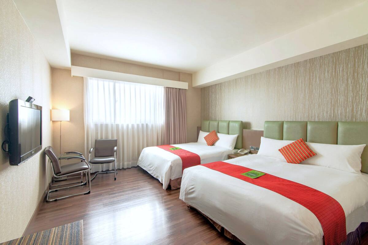 Une chambre d’hôtel avec deux lits, une télévision, un bureau et une chaise.
