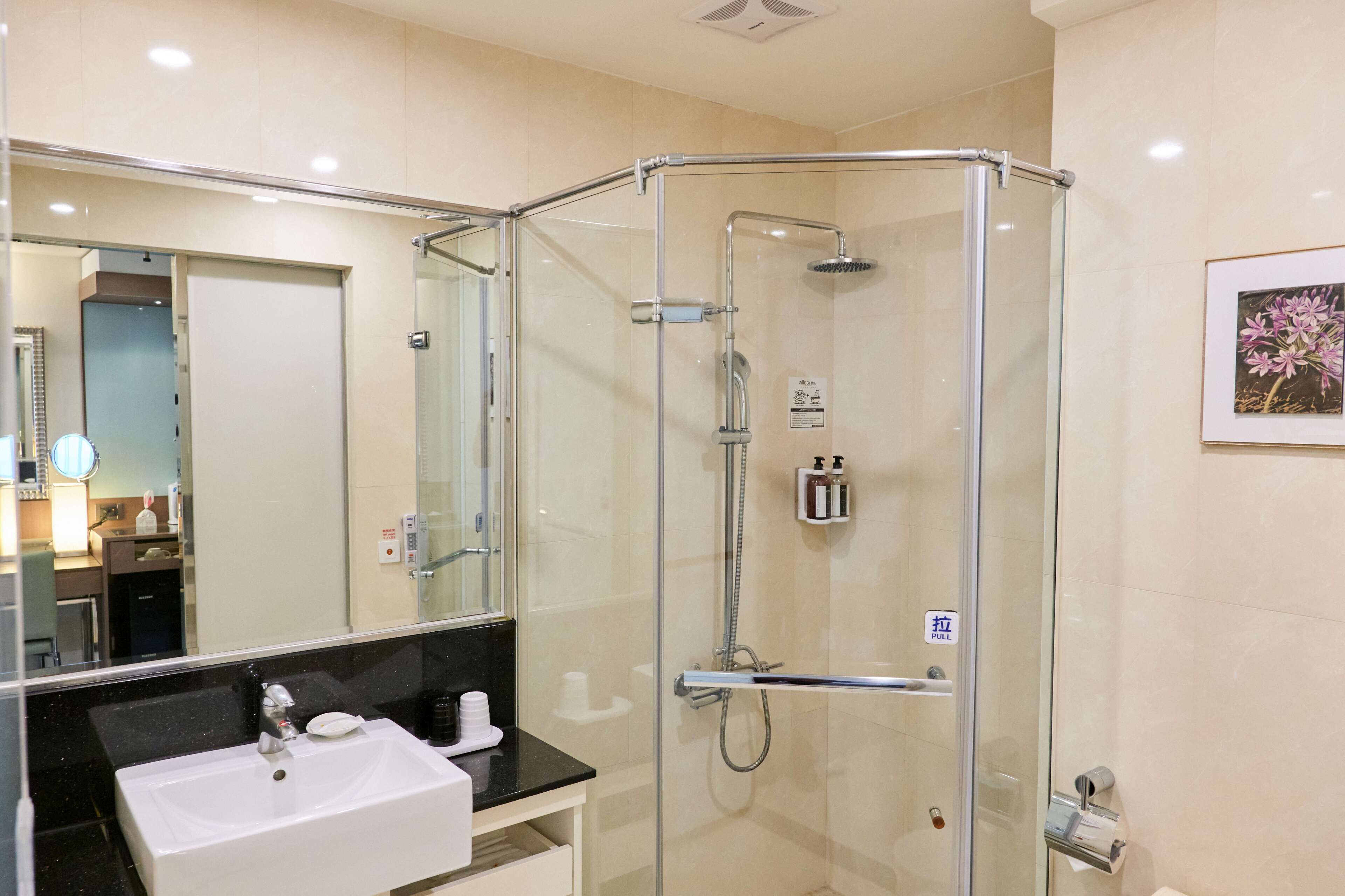 A modern bathroom with a glass-enclosed shower, a sink with a black countertop, and a large mirror.