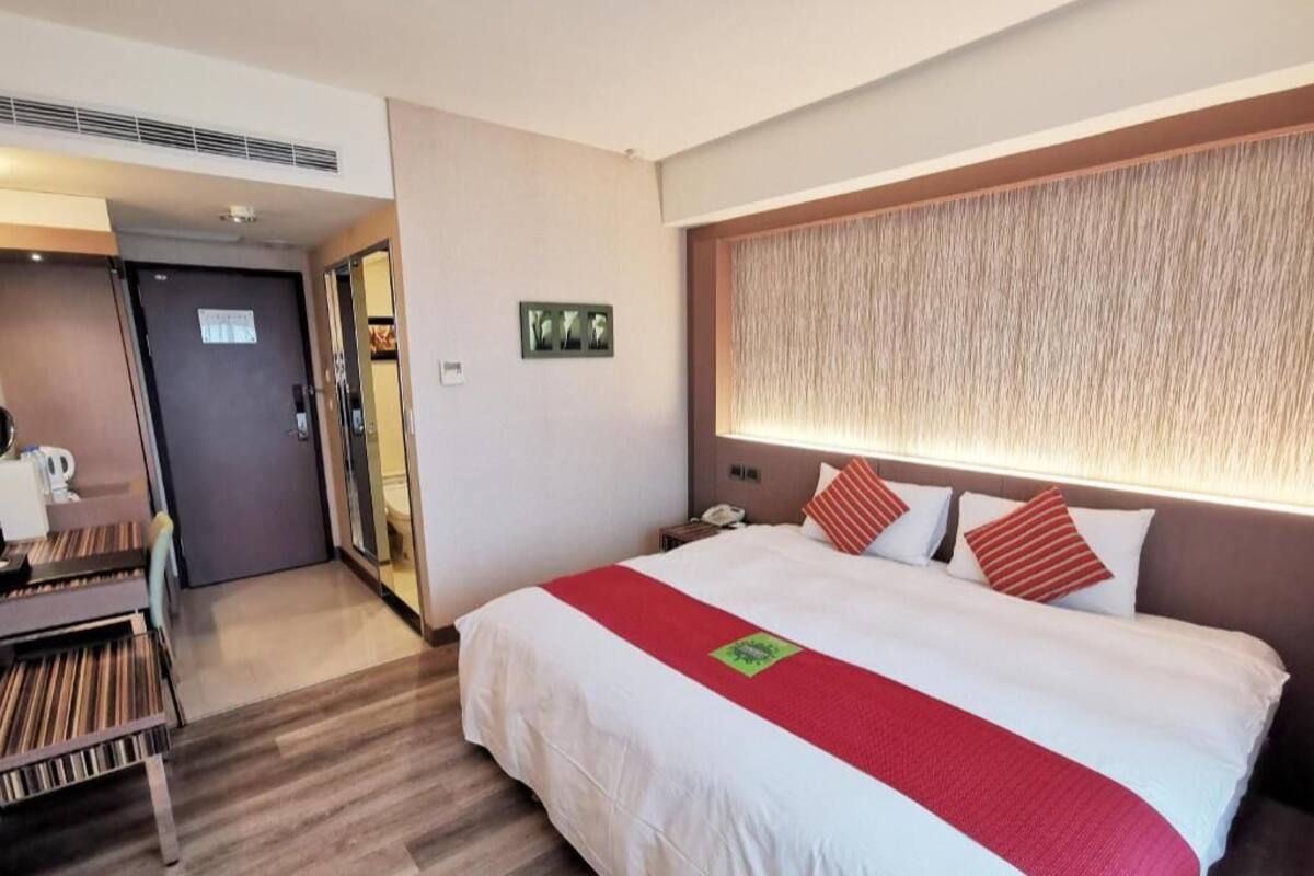 Une chambre d’hôtel avec un lit, un bureau et une porte donnant sur une salle de bain.