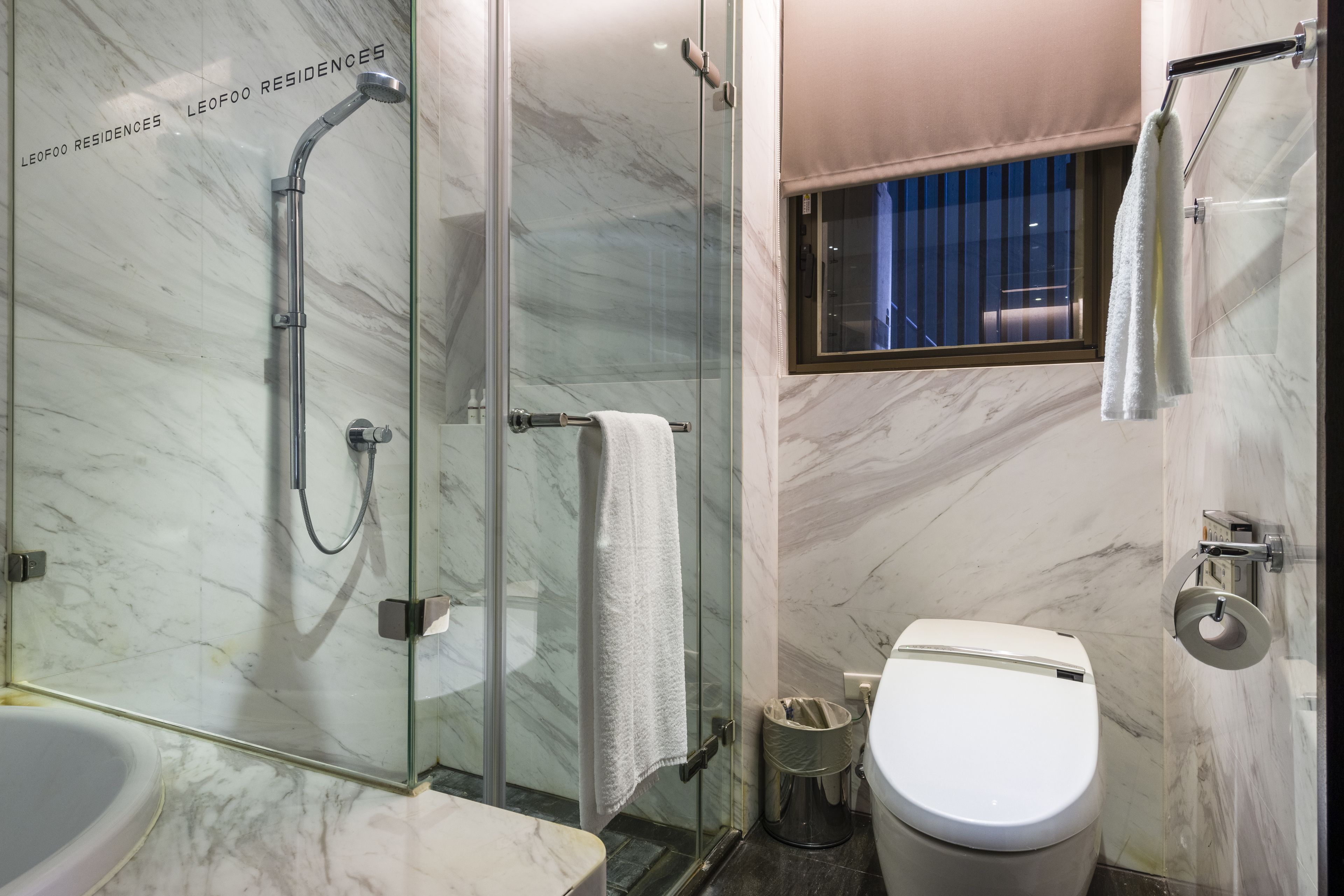Une salle de bain avec une douche à parois de verre, des toilettes et un lavabo.