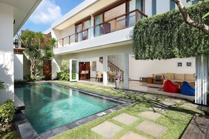 A modern house with a swimming pool, a covered patio, and a staircase leading to a second floor.