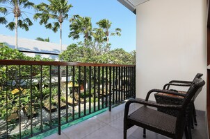 Varanda com vista para uma piscina, rodeada por vegetação exuberante e palmeiras.