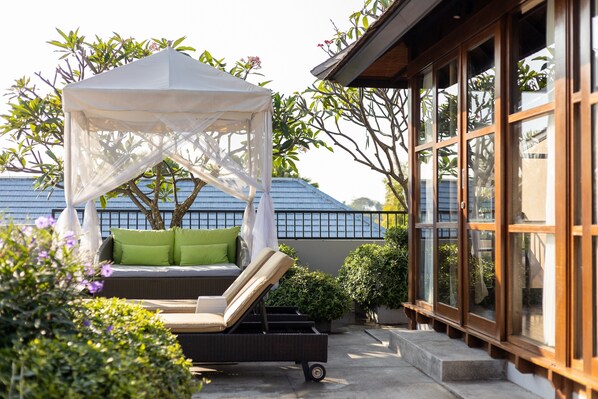 A sunlit outdoor seating area with a canopy, a lounge chair, and a small table. - Amadea Resort & Villas (Seminyak)