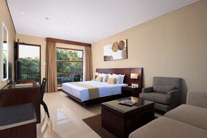 Habitación de hotel con una cama grande, un escritorio, una silla, un sofá y una ventana con cortinas.