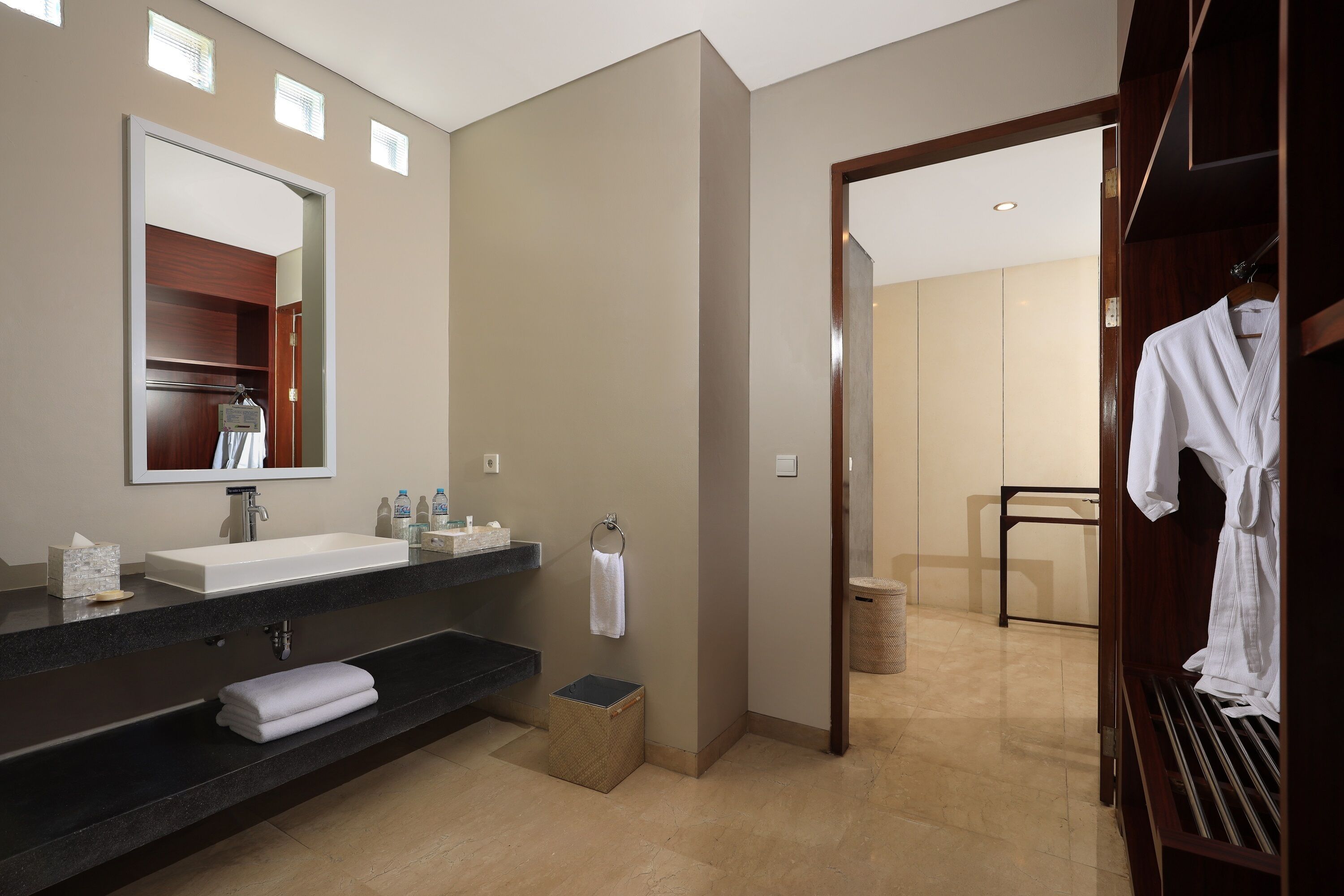 Un bagno moderno con un grande specchio, due lavabi, un portascopevoli e un mobile bagno in legno.