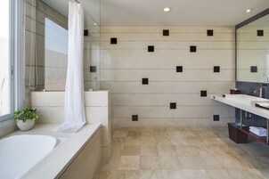 Un bagno moderno con una vasca da bagno ampia, una doccia e un lavandino. Sul davanzale c'è una pianta in vaso e un porta asciugamani.
