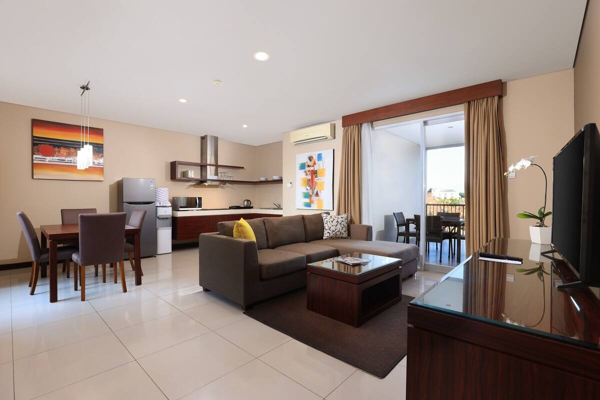 A modern living room with a sofa, coffee table, TV, and dining area.