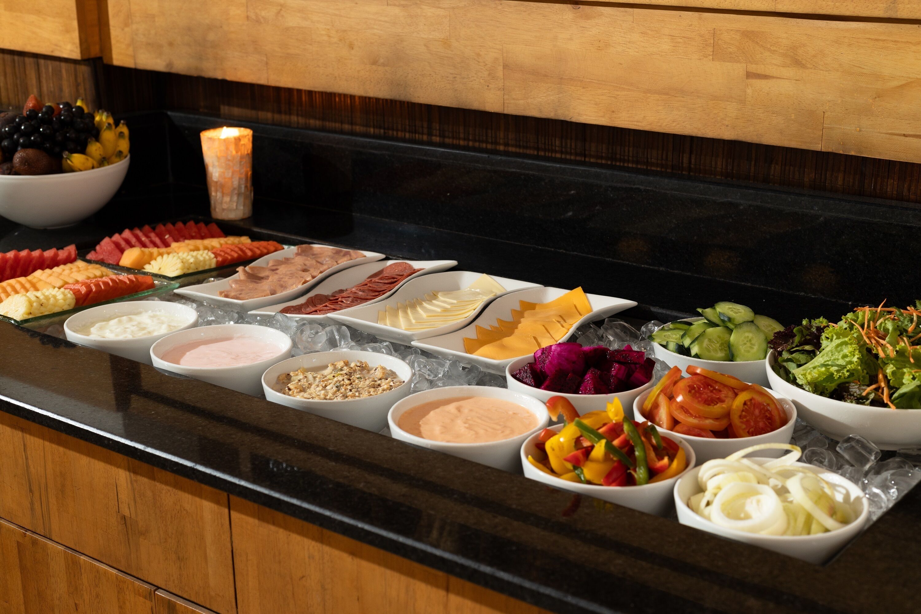 Ein Buffet mit verschiedenen Speisen, darunter Obst, Gemüse, Käse und Fleisch.