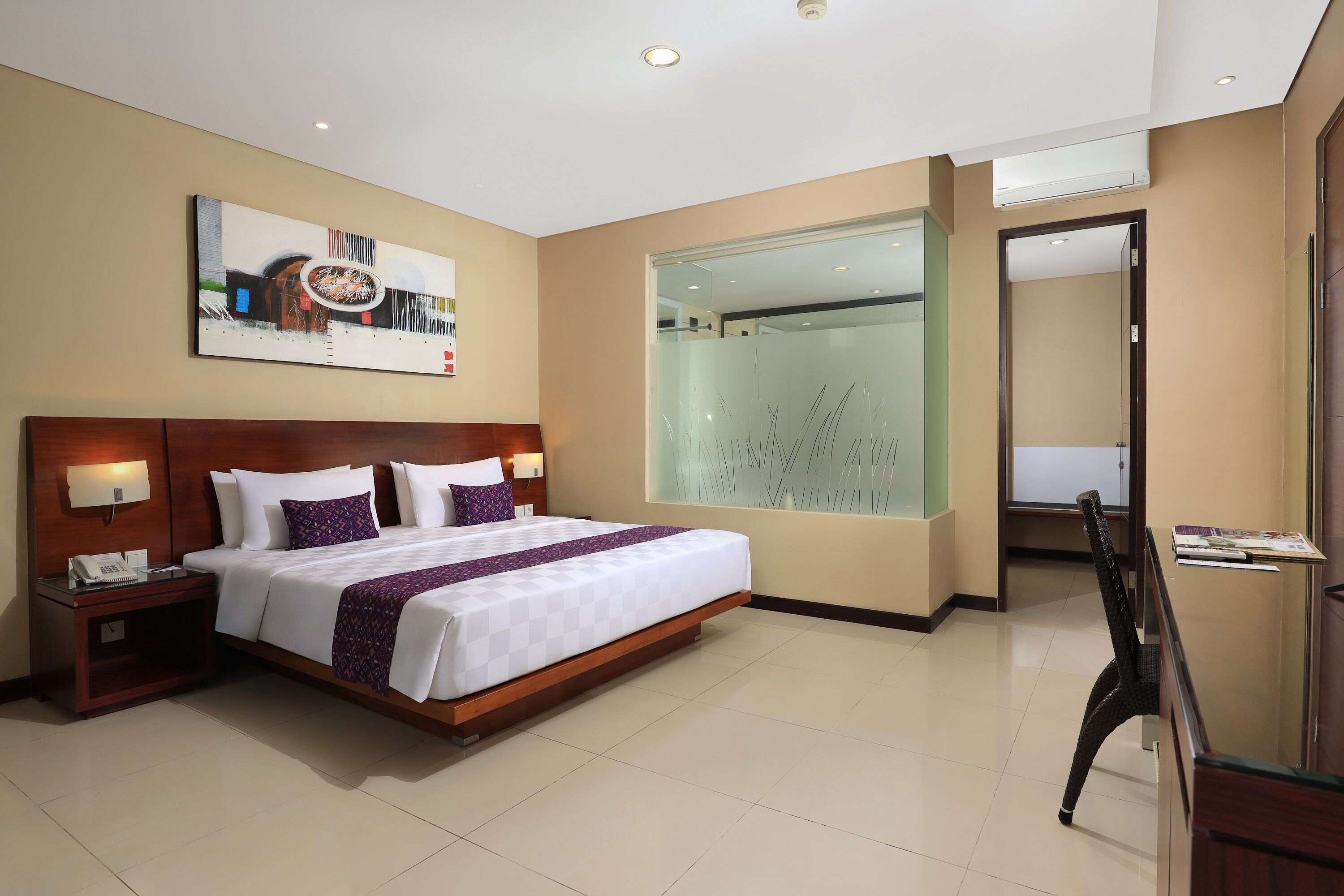 A hotel room with a large bed, bedside tables, a glass shower enclosure, and a desk with a chair.