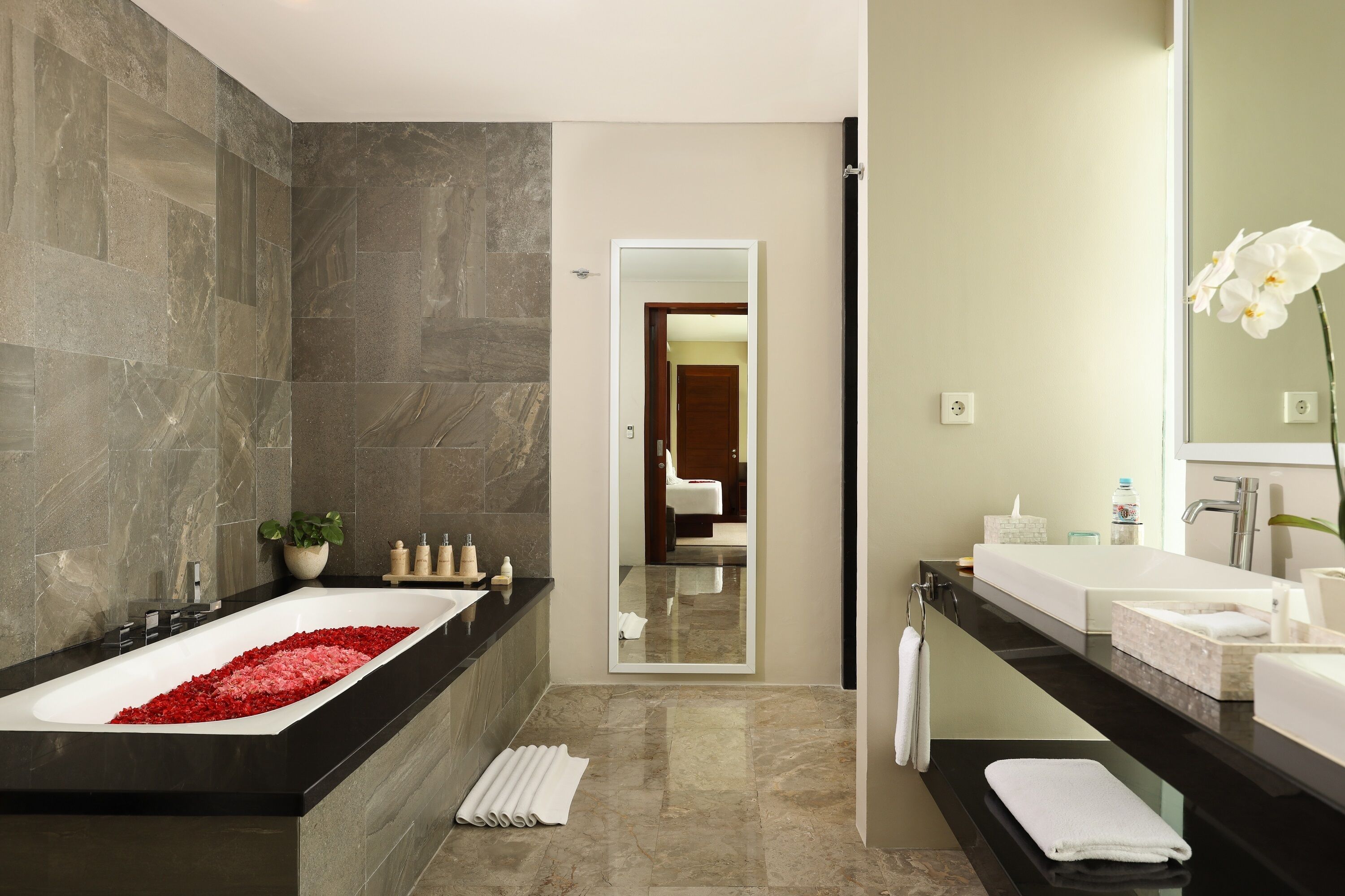 A modern bathroom with a large bathtub, a separate sink area, and a mirror.