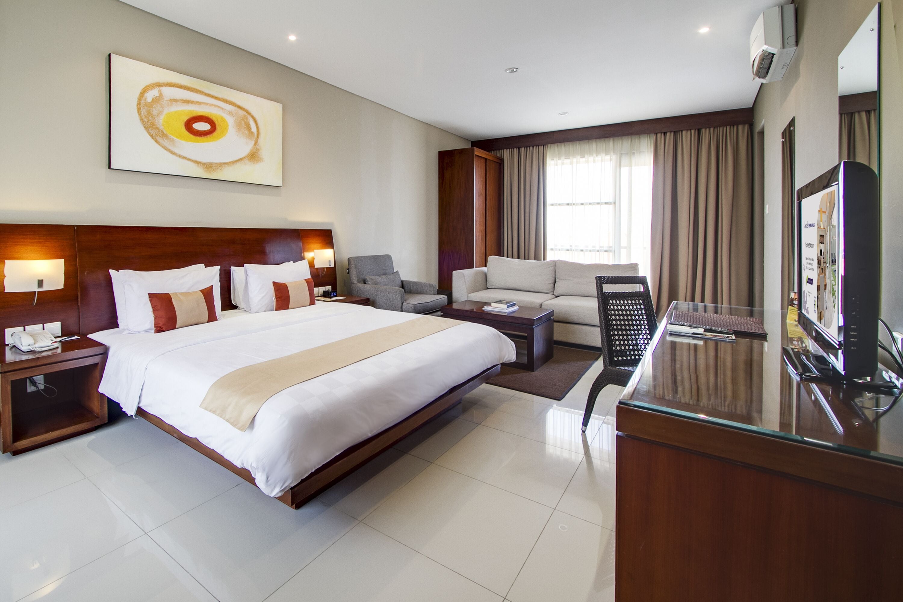 A hotel room with a large bed, a sofa, a desk, and a TV.