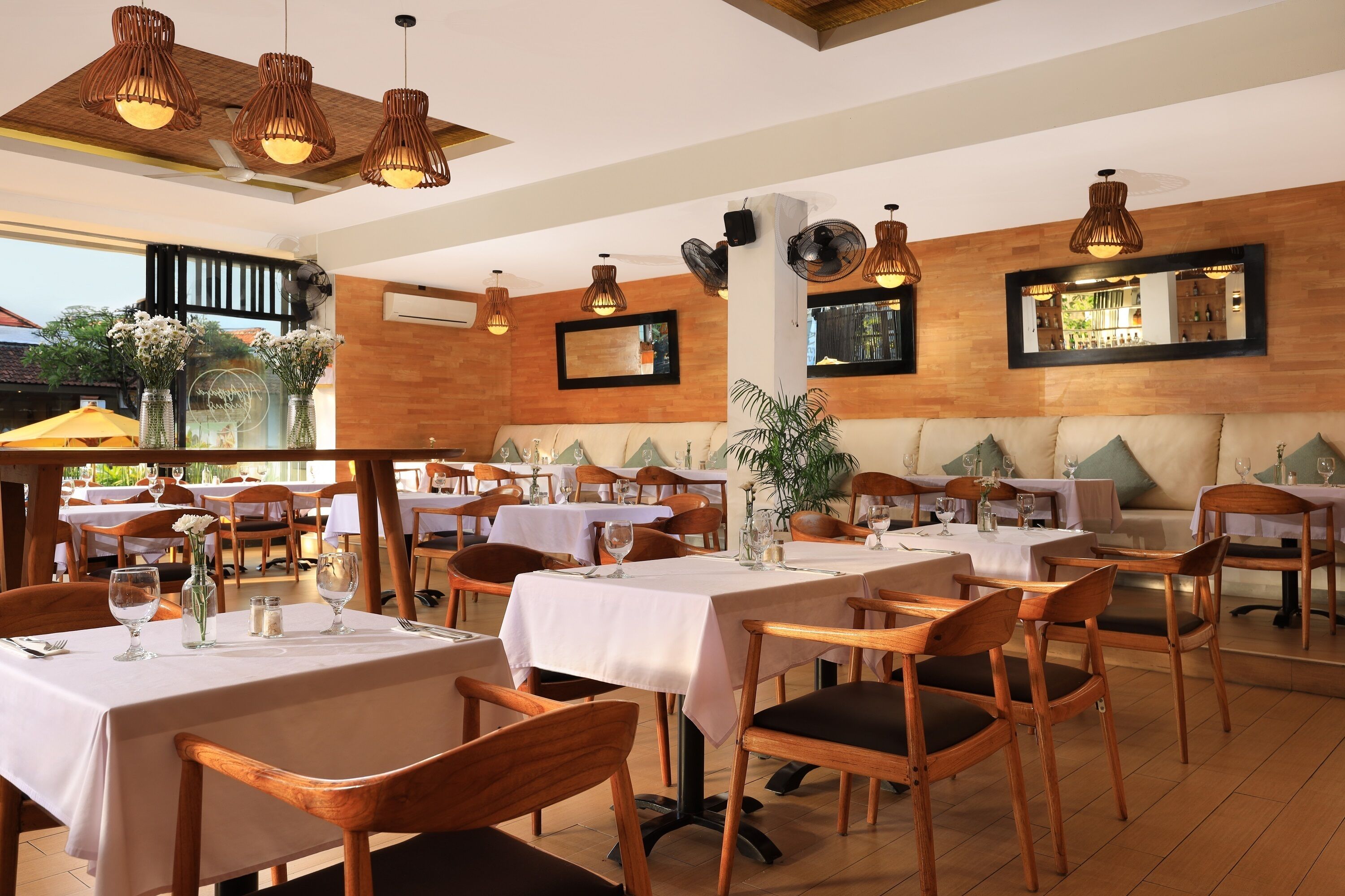 A restaurant with wooden tables, chairs, and hanging wicker lamps.