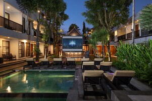 A poolside area with lounge chairs, a bar, and a large screen for outdoor movies.