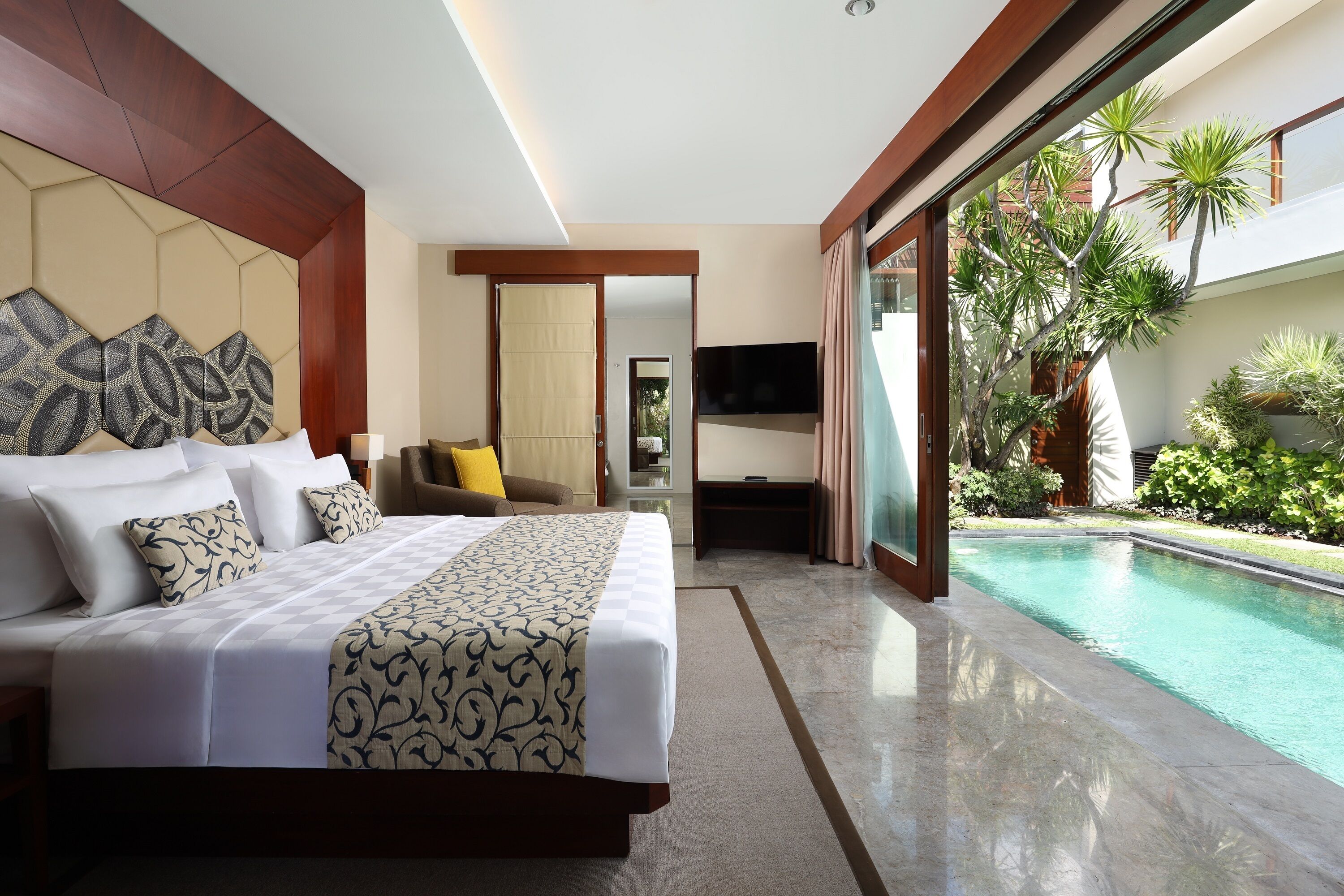 A modern hotel room with a large bed, a TV, and a view of a swimming pool.