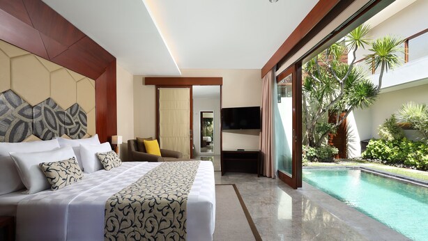 Una habitación de hotel moderna con una cama grande, un televisor y vistas a una piscina.