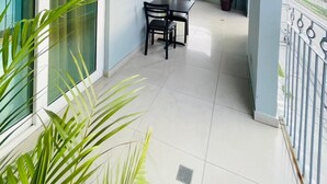 Een balkon met een tafel en stoelen, plantenbakken en uitzicht op de stad.