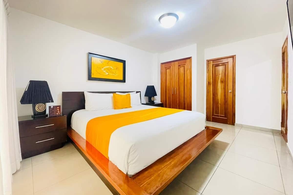 Ein Hotelzimmer mit einem großen Bett, einem Holzschrank und einem Nachttisch mit Lampe.